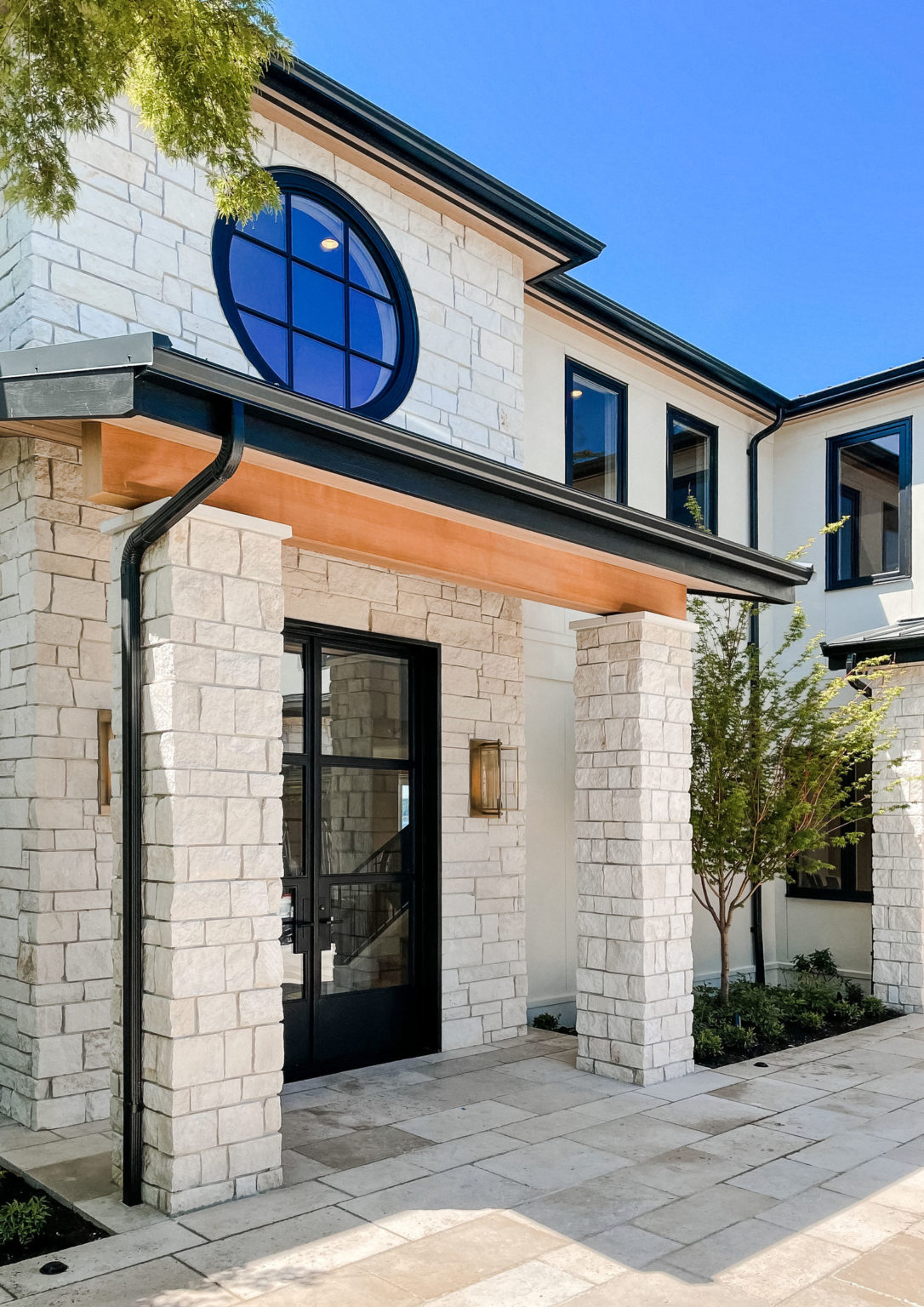 Stone veneer beside smooth stucco and black-framed glass on the Pella Stone project