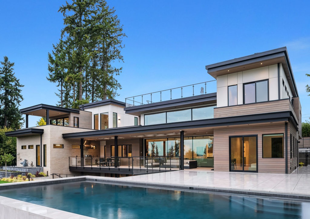 Modern home exterior with brickwork beside large glass doors and a pool