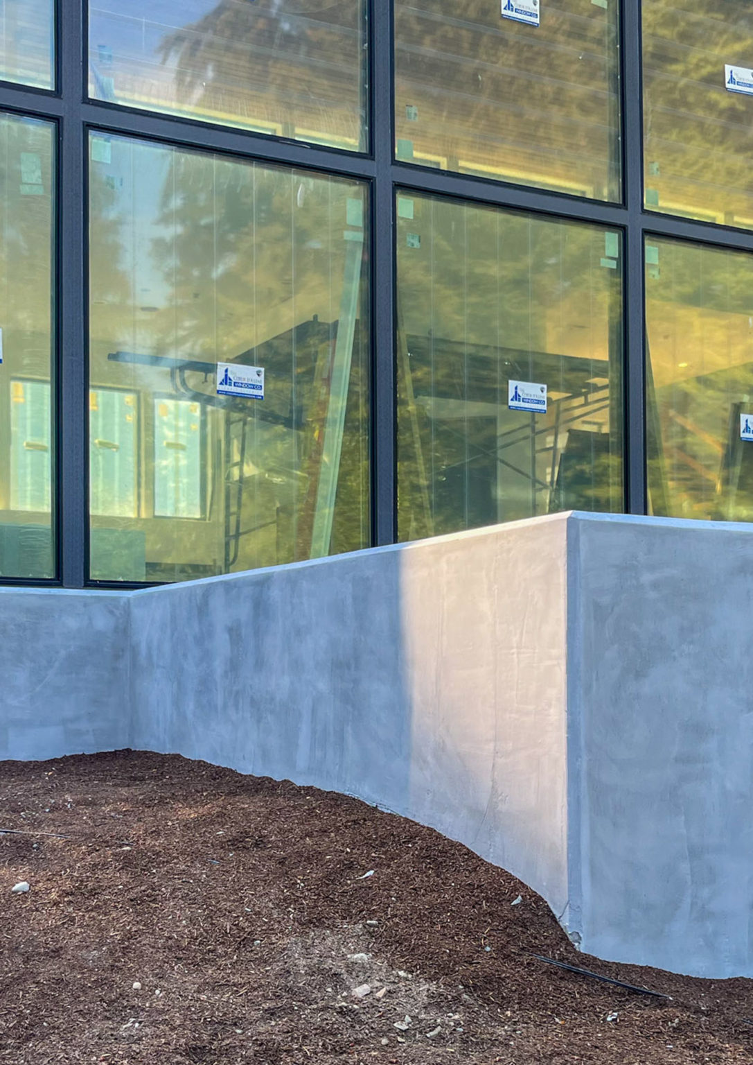 Smooth gray stucco wall detail beside large windows in the Seattle Gray project
